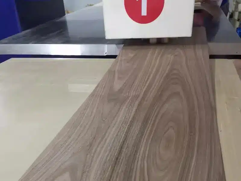 Customized wood veneer sheet being processed under a veneer pressing machine