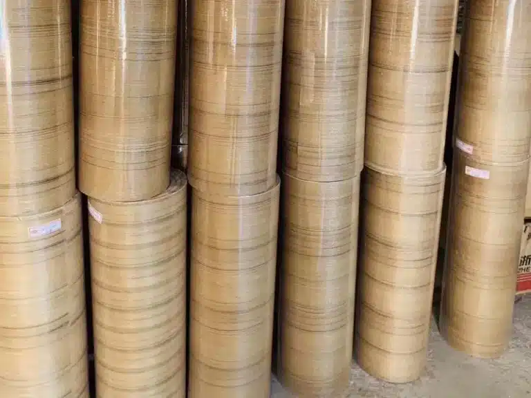 Stacks of light wood grain paper-backed veneer rolls